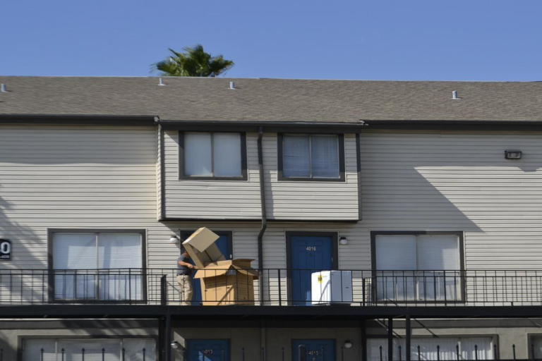 Man moving boxes in front of house